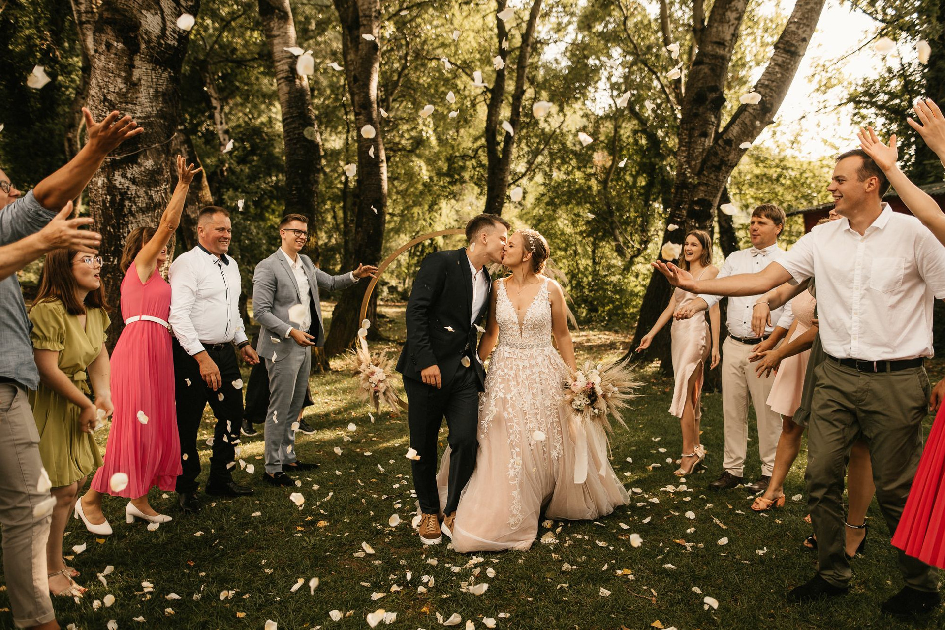 Newlyweds walking beneath trees at their celebration.